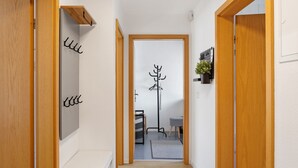 A hallway with wooden doors, a coat rack, a small table, and a plant. - Holiday Apartment 'Kleinbreitenbach 2' with Mountain View and Wi-Fi (Plaue)