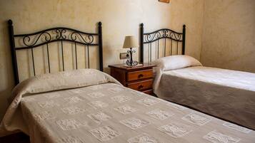 Un dormitorio con dos camas individuales, una mesita de noche con lámpara y un aparador de madera.