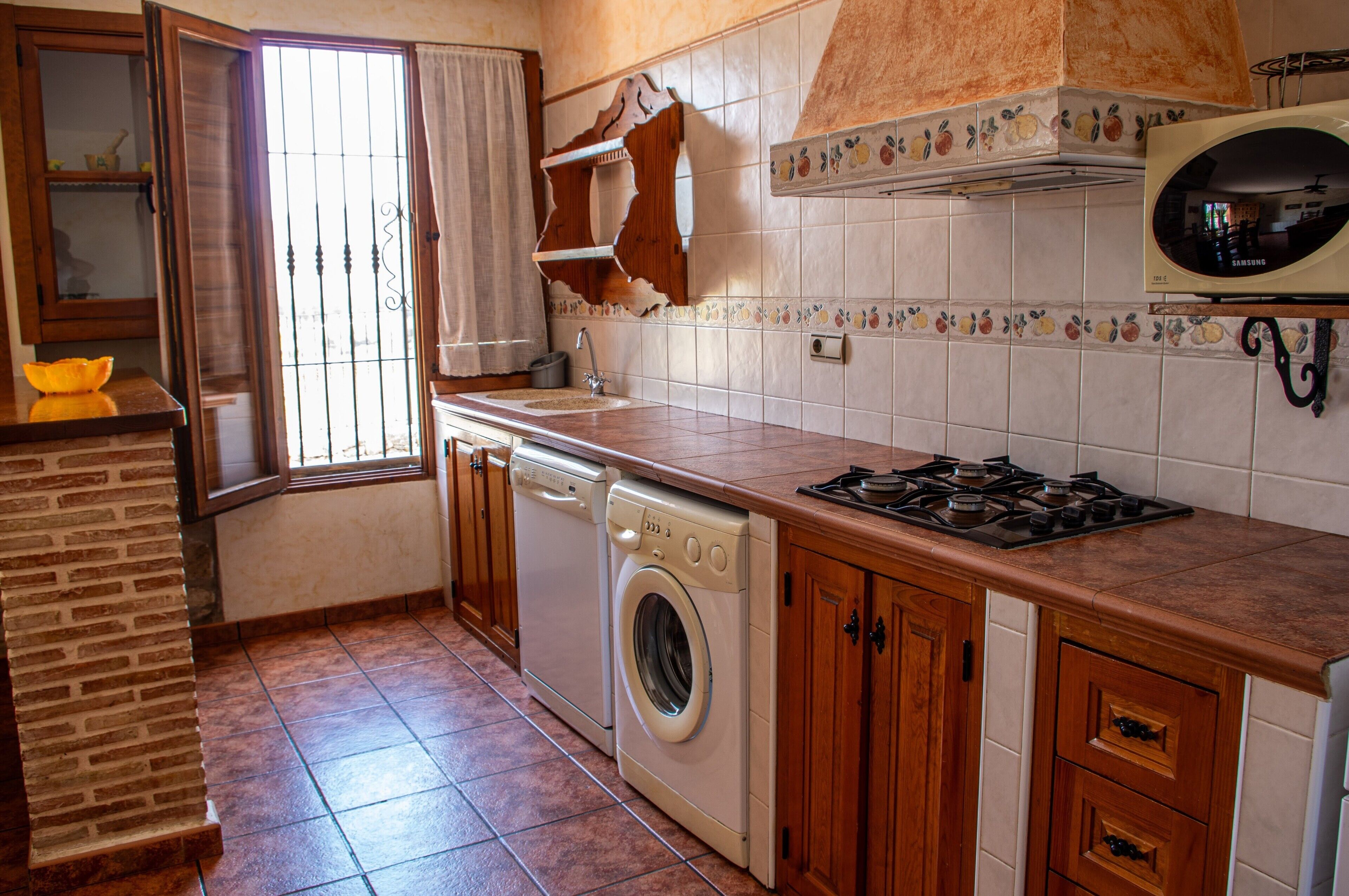 Een keuken met een wasmachine, een fornuis en een magnetron.