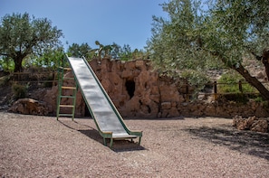 A playground with a slide, a ladder, and a rocky wall.