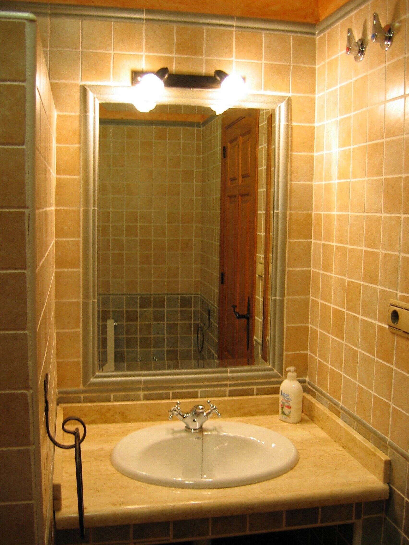 A bathroom with a sink, mirror, and tiled walls.