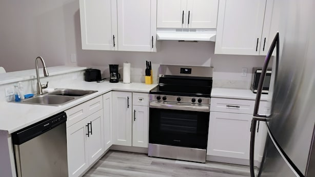 A modern kitchen with white cabinets, stainless steel appliances, a dishwasher, and a refrigerator.