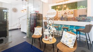 Un espace bar moderne avec une enseigne « BIENVENIDOS », une cloison en verre et un mur orné d’un motif bleu.