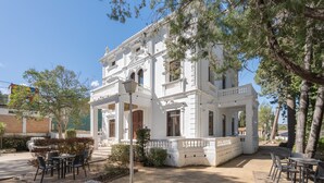 A white building with a balcony, outdoor seating, and trees. - Room 'Esmeralda' with Mountain View, Wi-Fi and Air Conditioning (Navajas)