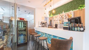 A bar area with stools, a refrigerator with bottles, a coffee machine, and a green wall. - Room 'Esmeralda' with Mountain View, Wi-Fi and Air Conditioning (Navajas)