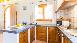 Une cuisine avec des meubles en bois, un four à micro-ondes et une cuisinière à gaz.
