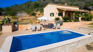 Une piscine avec des chaises longues, un espace patio et une maison avec un toit en tuiles.