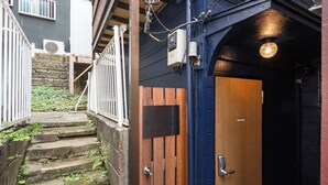 A narrow stairway leading to a wooden door with a metal handle, surrounded by a blue exterior wall and a white railing. - EBISU BLUE Ebisu Station 8 min walk / Quiet residential area Ebisu is one of the most popular and elegant residential areas in Tokyo where everyone wants to live.  (渋谷区)