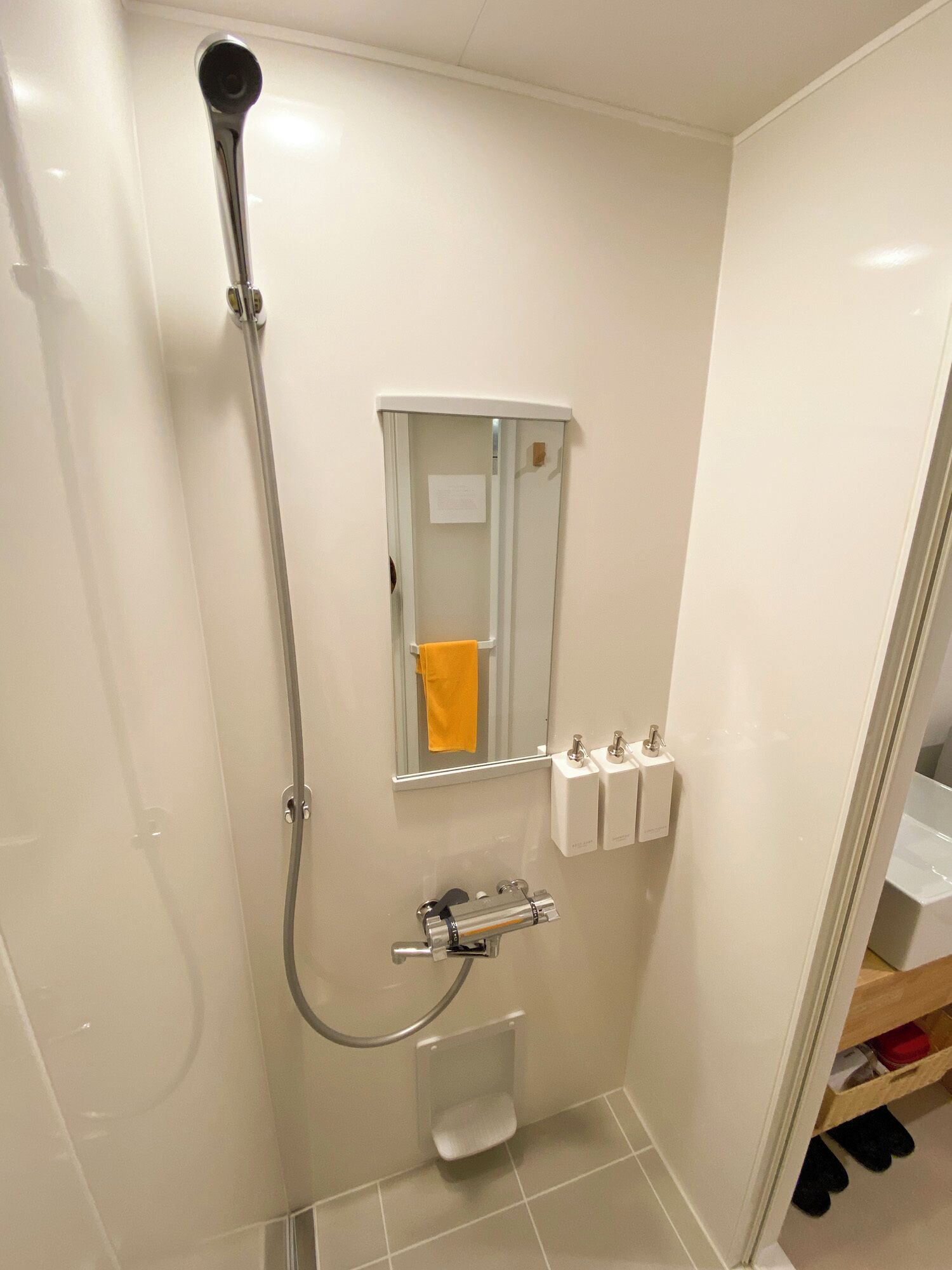 A small bathroom with a shower, toilet, and a mirror.