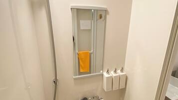A small bathroom with a shower, toilet, and a mirror.