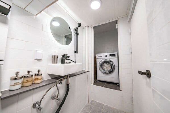 Un baño pequeño con lavabo, espejo y lavadora integrada.
