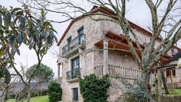 A stone building with a balcony, a grassy yard, and a potted plant. - Apartment 'Casa Rural Os Carballos' with Private Pool, Wi-Fi and Air Conditioning (Pontevedra)