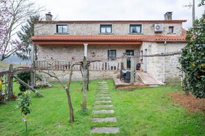 A stone building with a tiled roof, a stone staircase leading to a door, and a garden with a stone path. - Apartment 'Casa Rural Os Carballos' with Private Pool, Wi-Fi and Air Conditioning (Pontevedra)