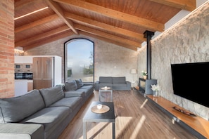 Ein moderner Wohnraum mit Holzboden, Steinwand und einem großen Fernseher.
