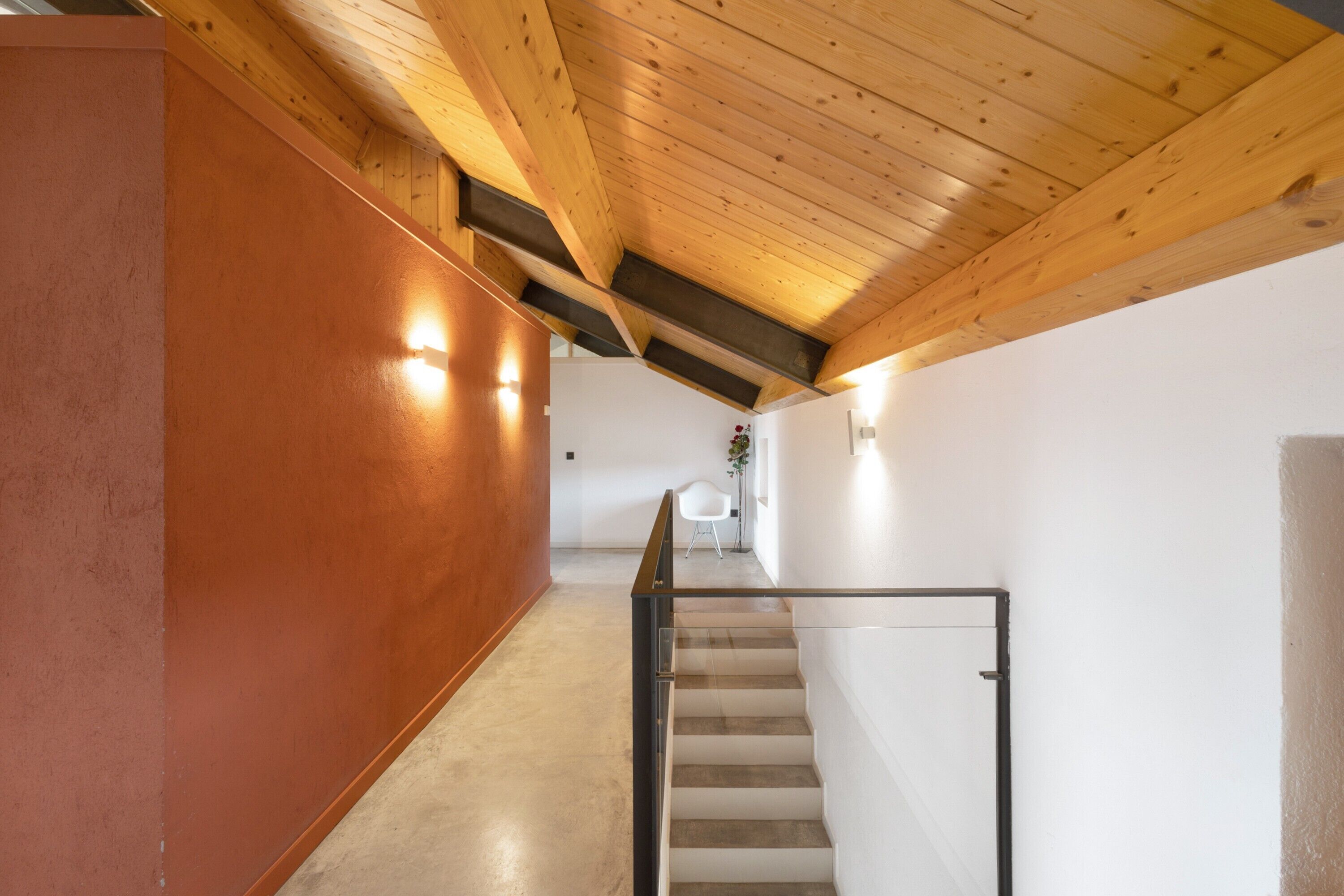 Un interior moderno con techo de madera, una escalera y una pared blanca.