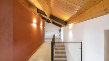 Un interior moderno con techo de madera, una escalera y una pared blanca.