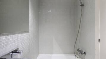 Un baño con bañera, ducha y espejo.