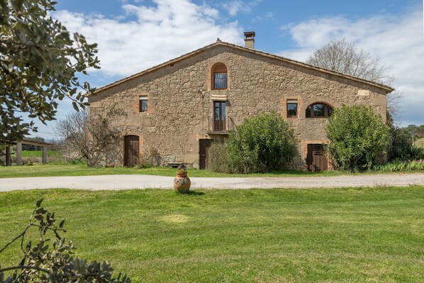A stone building with a central balcony, a door, and a window.