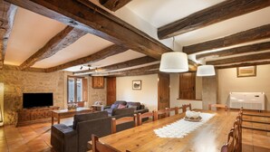A spacious living area with a wooden dining table, sofas, and a television.