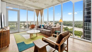 Un balcon spacieux avec de grandes fenêtres, un canapé, une table basse et un fauteuil.
