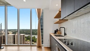 Une cuisine moderne avec une grande fenêtre, une vue sur les immeubles et une rivière, et un plancher en bois.