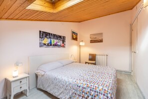 Une chambre à coucher avec un lit, une table de chevet, une lampe et des œuvres d’art murales.