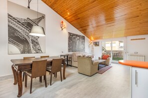 A spacious living area with a wooden ceiling, a dining table with chairs, a sofa, and a kitchen area with a countertop. - Apartment 'Tremp' with Mountain View, Wi-Fi and Air Conditioning (Tremp)