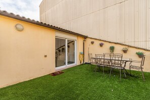 Une terrasse avec une table et des chaises, une porte-fenêtre coulissante et des plantes en pot.