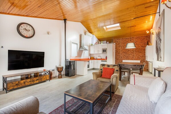 Un salon moderne avec un téléviseur à écran plat, une table basse en bois et un canapé.