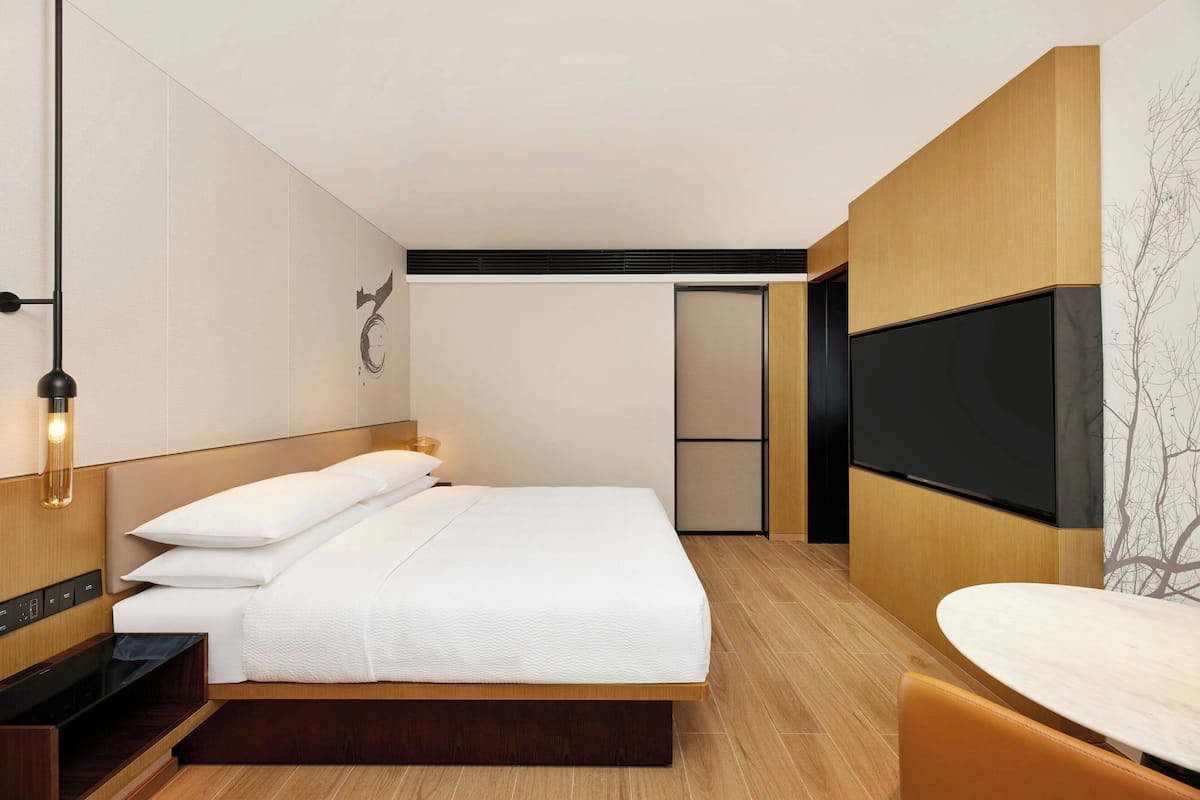 Una habitación de hotel moderna con una cama, televisión, escritorio y una silla.