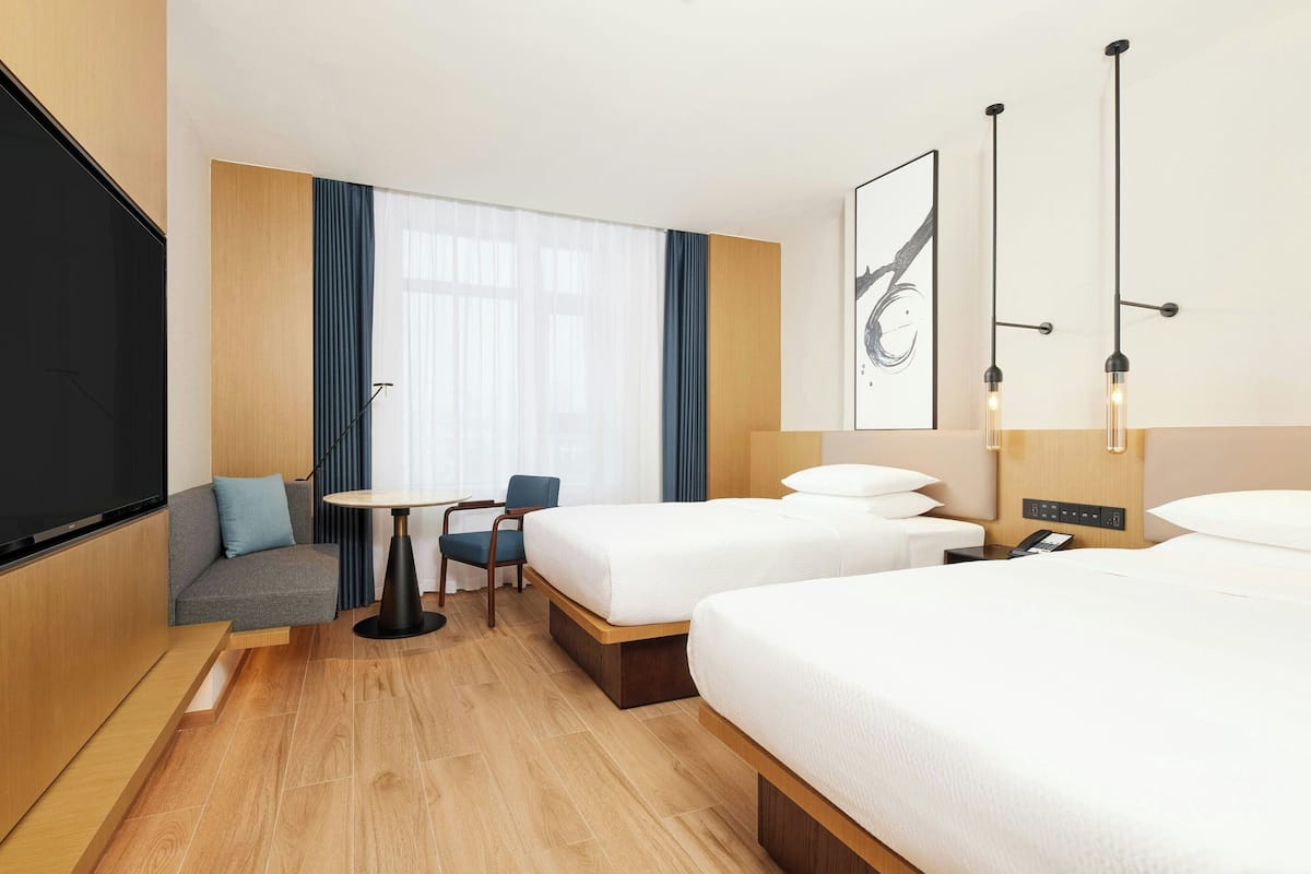 Una habitación de hotel con dos camas, un sofá, una mesita y un televisor.