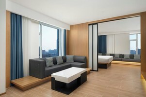 Una habitación de hotel moderna con un sofá modular, una mesita y un ventanal con vistas a la ciudad.