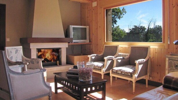 Una sala de estar acogedora con chimenea, asientos cómodos y un amplio ventanal con vistas al exterior.
