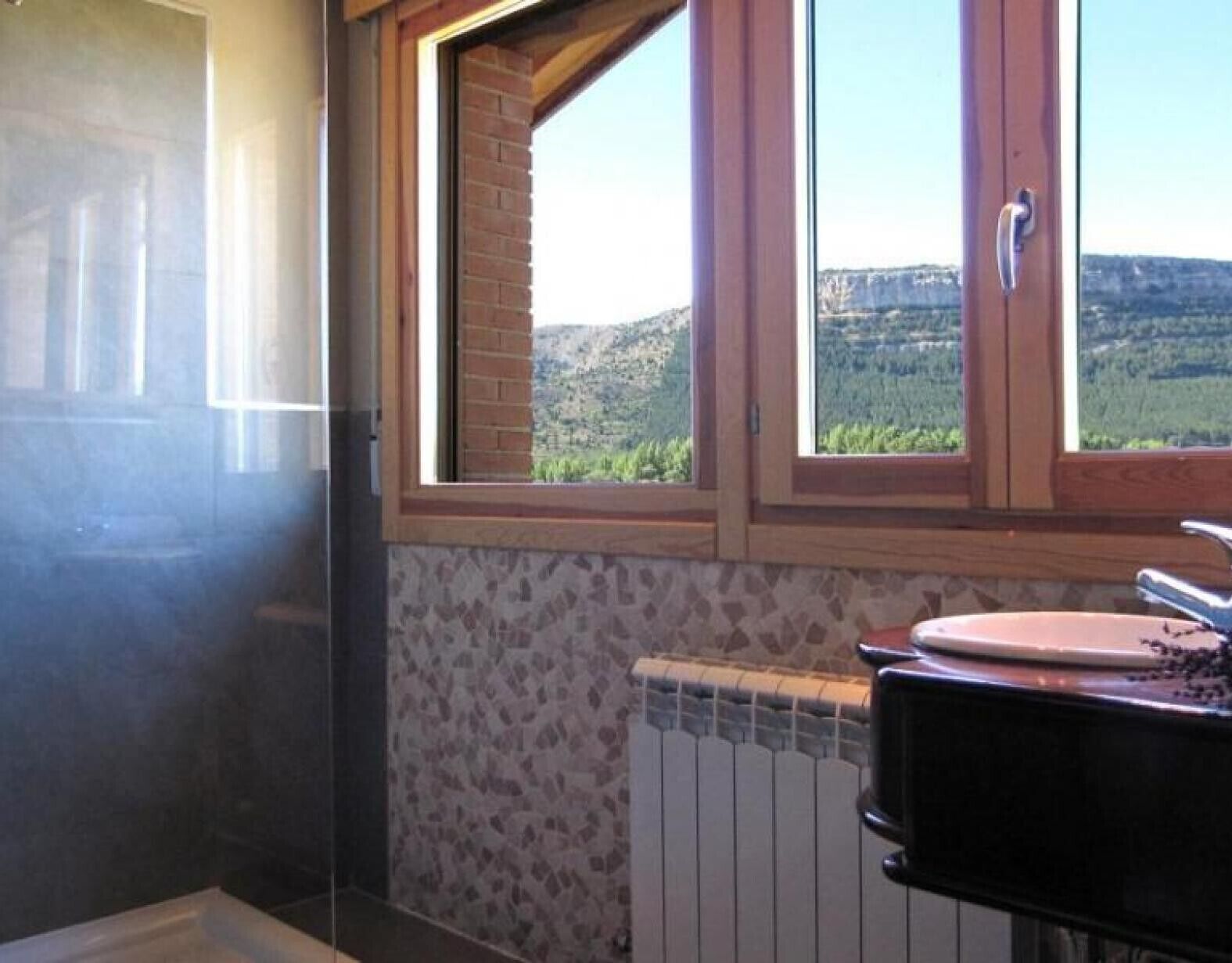 Une salle de bain avec une fenêtre, un radiateur et un lavabo.