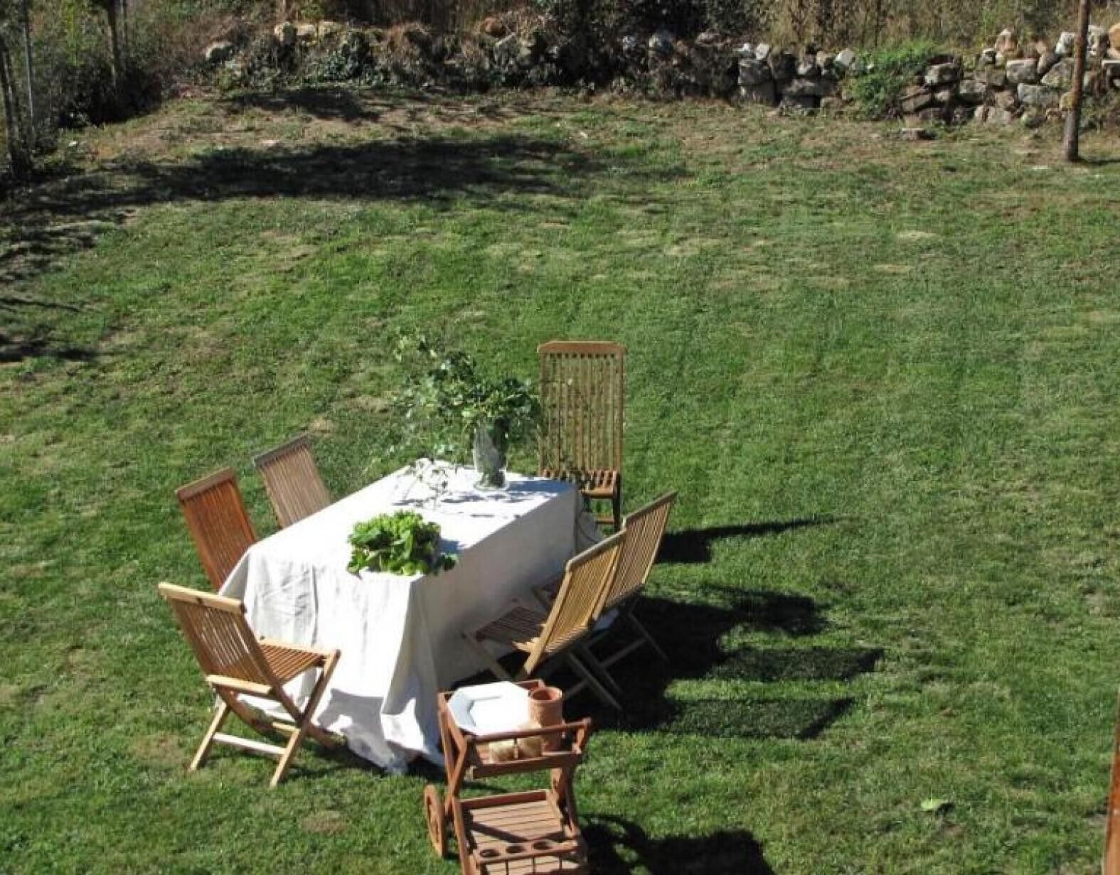 Un área de comedor al aire libre con una mesa dispuesta para cuatro personas, rodeada de sillas.