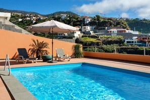 A swimming pool with lounge chairs and a view of a hillside town.
