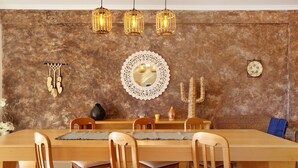 A dining area with a wooden table, chairs, a decorative mirror, and wall-mounted lights.