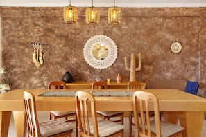 A dining area with a wooden table, chairs, a decorative mirror, and wall-mounted lights.