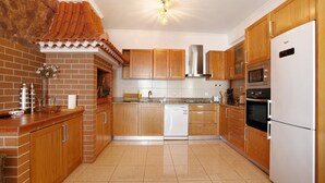 A kitchen with wooden cabinets, a white refrigerator, and a tiled floor.