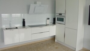 A modern kitchen with white cabinetry, a stainless steel sink, a built-in oven, and a microwave.