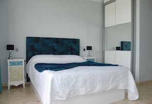 A bed with a white quilt, a blue headboard, and two bedside tables with lamps. - Vacation Home "Villa Bea I" with Mountain and Sea View, Wi-Fi, Garden & Terrace (San Bartolomé)