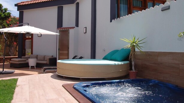 A modern house with a hot tub, outdoor seating, and a patio.