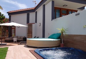 Una casa moderna con jacuzzi, mobiliario exterior y terraza.