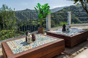 A terrace with wooden benches, a potted plant, and a lantern. - Vacation Home 'Casa Rural El Majano' with Mountain View, Private Pool and Wi-Fi (Moya)
