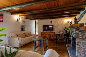 A cozy living room with a sofa, wooden coffee table, stone fireplace, and a television.