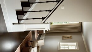 A staircase with a white railing and a window with curtains. - Charming 2-bedroom cottage with WiFi, AC in serene Miller Beach, IN (Gary)