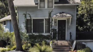 A two-story house with a front porch, steps, and a small garden. - Charming 2-bedroom cottage with WiFi, AC in serene Miller Beach, IN (Gary)