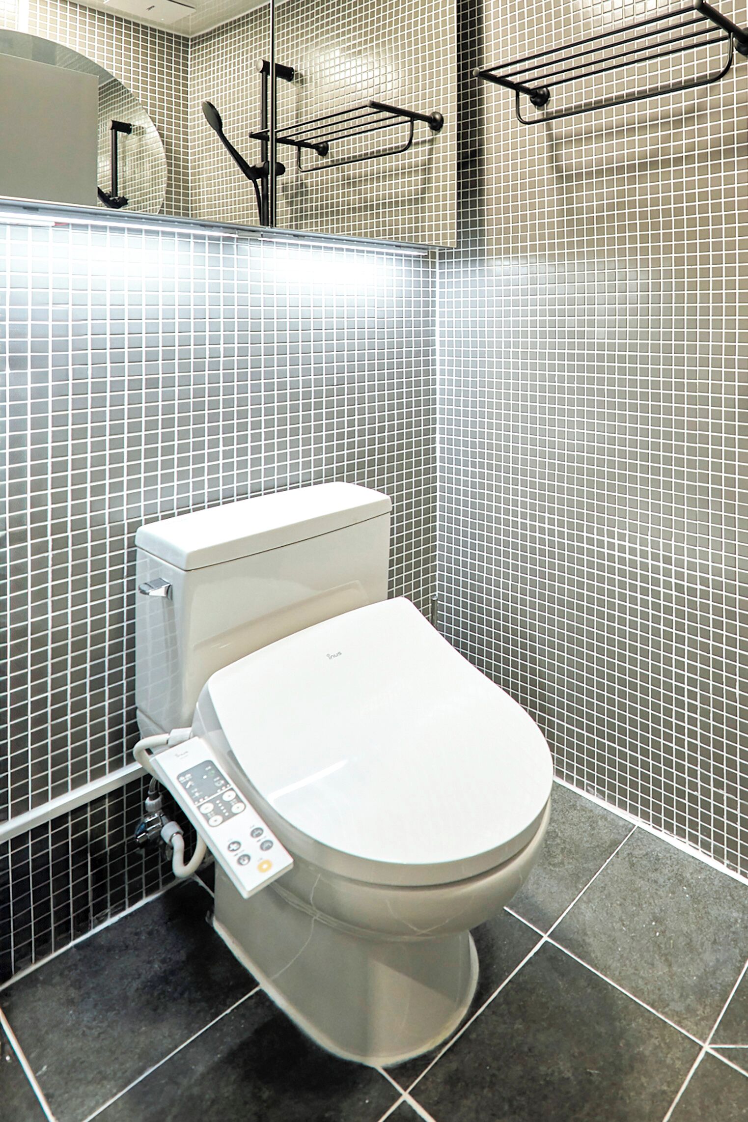 Un baño moderno con inodoro, panel de control y paredes con azulejos.