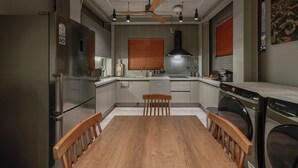 Una cocina compacta con una mesa de comedor, sillas de madera, horno empotrado y ventilador de techo.
