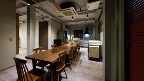 Una cocina moderna con una mesa y sillas de madera, horno empotrado y una ventana con persianas.